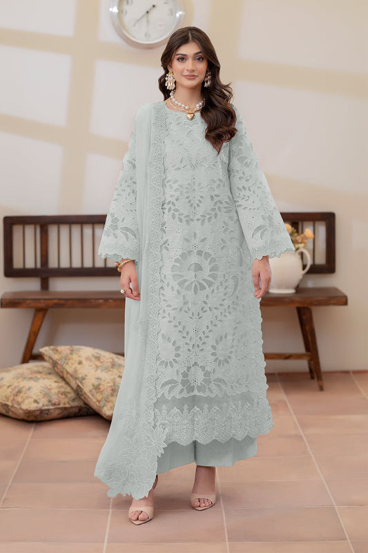 Woman wearing a light blue embroidered outfit in an indoor setting.