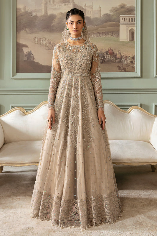 A woman wearing a beige and silver embroidered gown with long sleeves and a floor-length skirt, accessorized with a net dupatta.