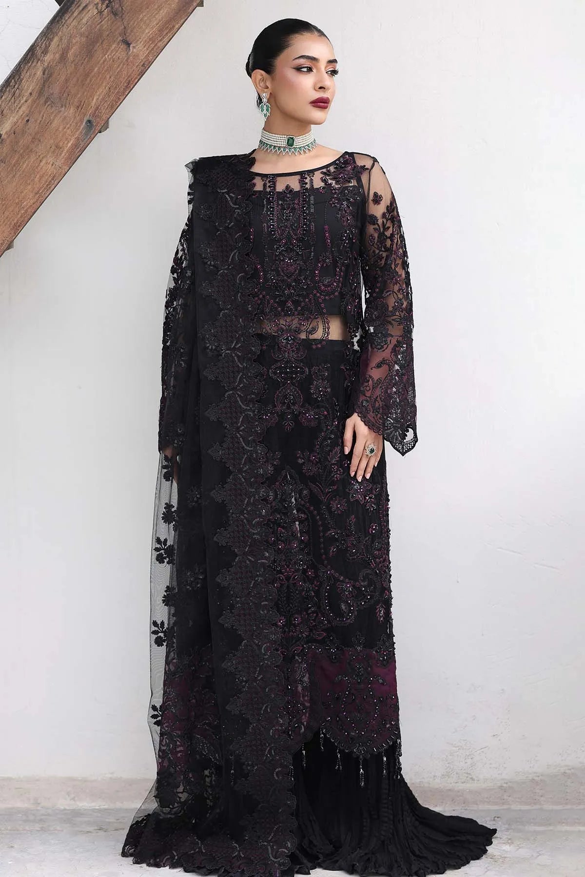 Woman wearing a black lace dress against a white wall